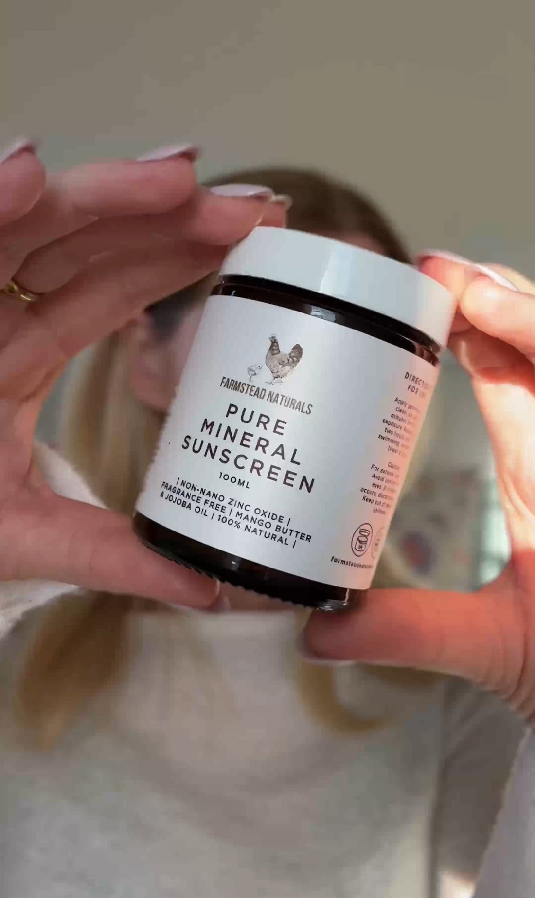 Young woman holding mineral zinc sunscreen for sensitive and rosacea-prone skin